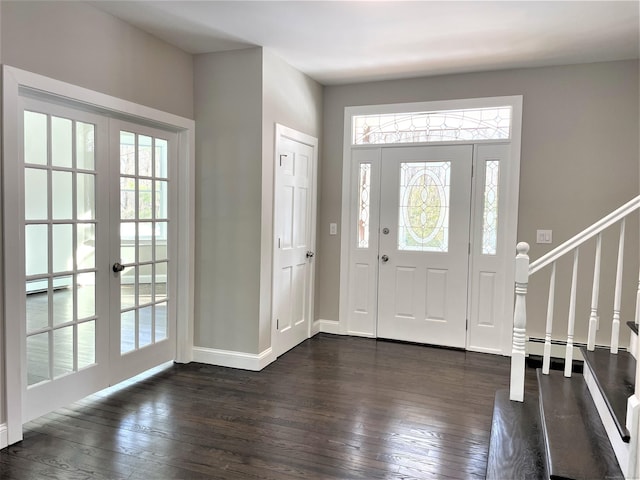 foyer entrance with stairs, a baseboard heating unit, dark wood-type flooring, and french doors