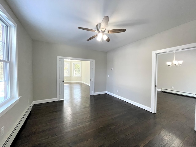 spare room featuring a baseboard heating unit, dark wood-style flooring, ceiling fan with notable chandelier, and baseboards