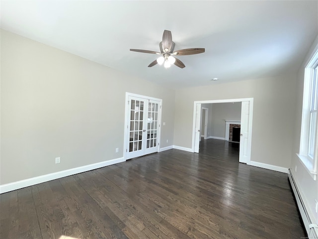 spare room with baseboard heating, a brick fireplace, dark wood finished floors, and baseboards