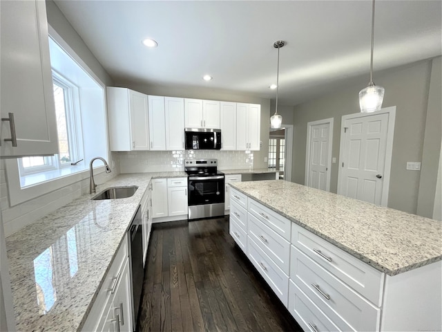 kitchen featuring a center island, dark wood-style flooring, backsplash, appliances with stainless steel finishes, and a sink