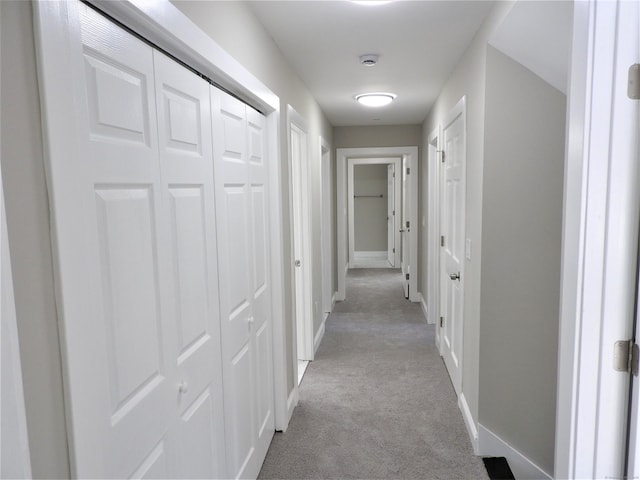 hallway featuring carpet and baseboards