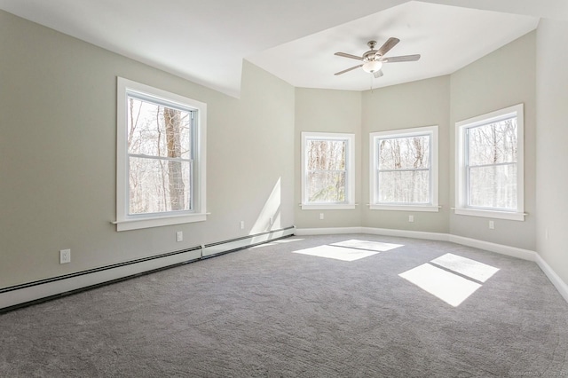 carpeted spare room with a baseboard heating unit, plenty of natural light, a ceiling fan, and baseboards