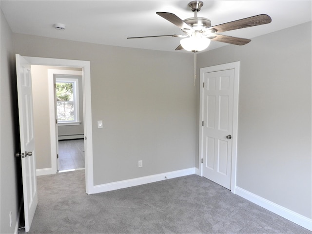 empty room featuring a baseboard heating unit, carpet, a ceiling fan, and baseboards