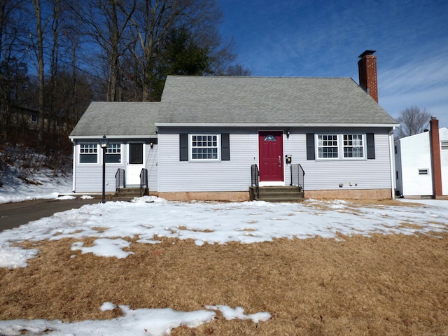 view of front of house with entry steps, a shingled roof, and a chimney