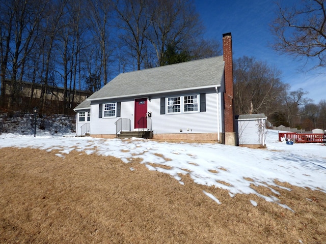 view of front of home featuring a shingled roof, an outdoor structure, a chimney, and a shed