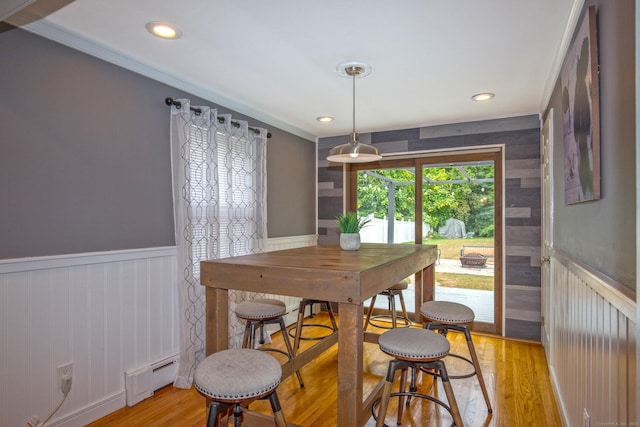 dining area with a wainscoted wall, a baseboard heating unit, and light wood-style floors