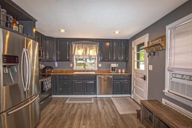 kitchen with dark wood finished floors, appliances with stainless steel finishes, a sink, light stone countertops, and a wealth of natural light