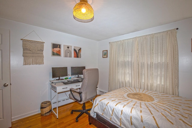 bedroom featuring a baseboard heating unit, baseboard heating, and wood finished floors