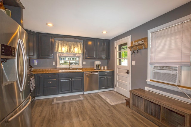 kitchen featuring light stone counters, cooling unit, a sink, appliances with stainless steel finishes, and dark wood finished floors