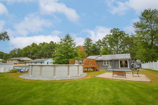 rear view of property with a yard, fence, a wooden deck, and an outdoor pool