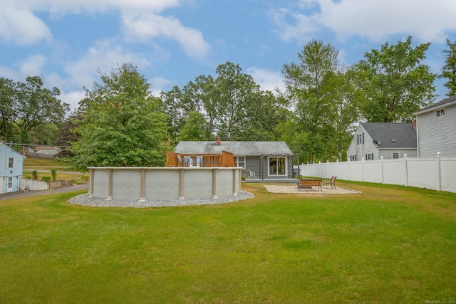 rear view of house with fence, a fenced in pool, and a yard