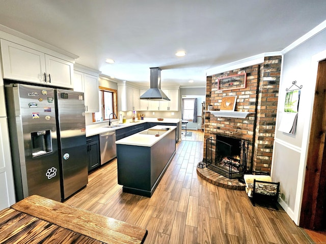 kitchen with a healthy amount of sunlight, island range hood, appliances with stainless steel finishes, and a sink