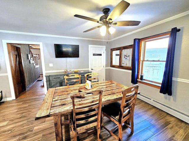 dining space with baseboards, a ceiling fan, wood finished floors, baseboard heating, and crown molding