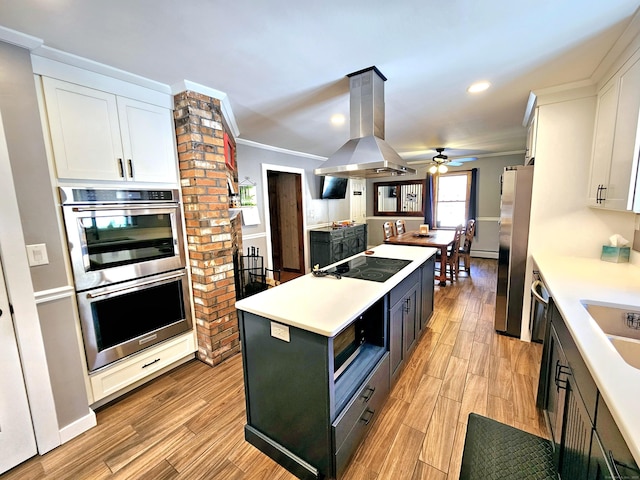 kitchen featuring crown molding, stainless steel appliances, island exhaust hood, and white cabinets