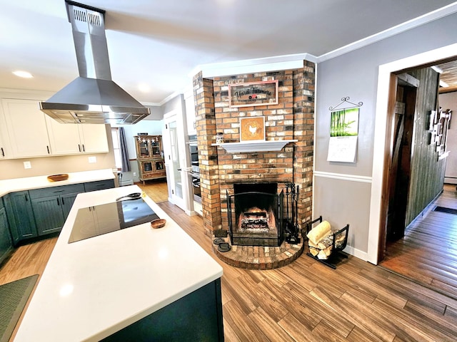 kitchen featuring light wood finished floors, ornamental molding, white cabinets, island range hood, and black electric cooktop