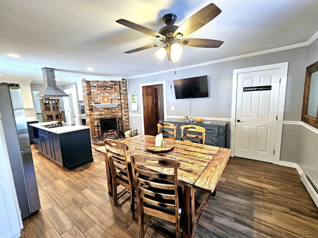 dining room featuring a baseboard heating unit, a fireplace, light wood-style flooring, and crown molding