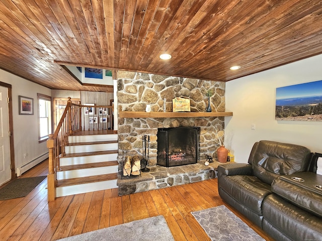 living room featuring wood ceiling, hardwood / wood-style floors, stairs, baseboard heating, and a fireplace