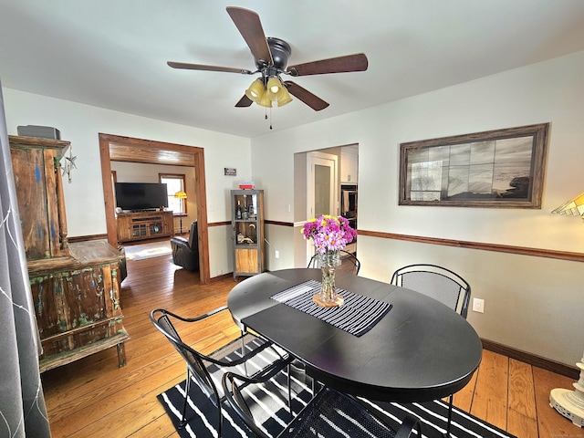 dining space with a ceiling fan, light wood-style flooring, and baseboards