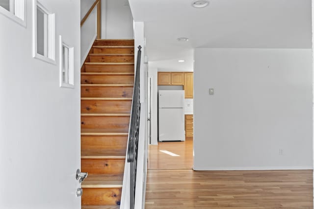 stairway with baseboards, wood finished floors, and recessed lighting