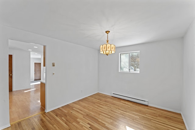 empty room featuring a baseboard heating unit, a chandelier, light wood-style floors, and baseboards