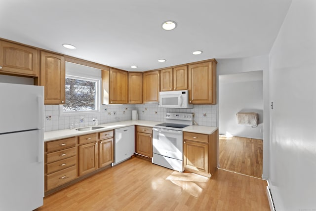 kitchen featuring white appliances, tasteful backsplash, light wood finished floors, light countertops, and a sink