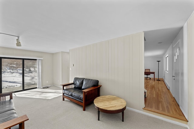 sitting room with a baseboard heating unit and light colored carpet