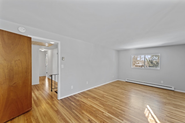 spare room featuring baseboards, a baseboard radiator, and light wood-style floors