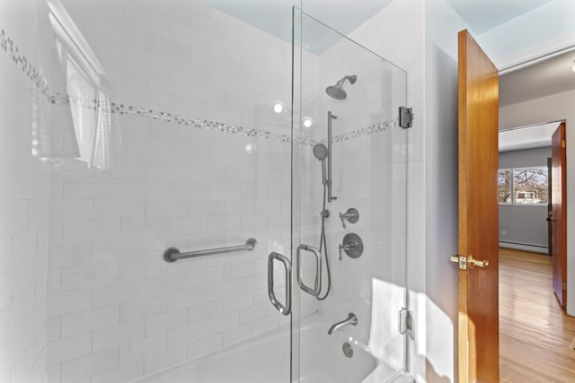 bathroom featuring a baseboard radiator, enclosed tub / shower combo, and wood finished floors