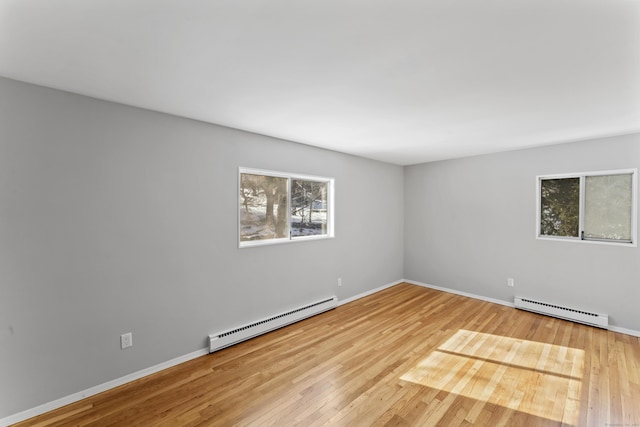 spare room featuring baseboards, baseboard heating, and wood finished floors