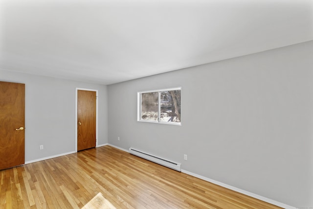 unfurnished bedroom featuring baseboards, baseboard heating, and light wood-style floors