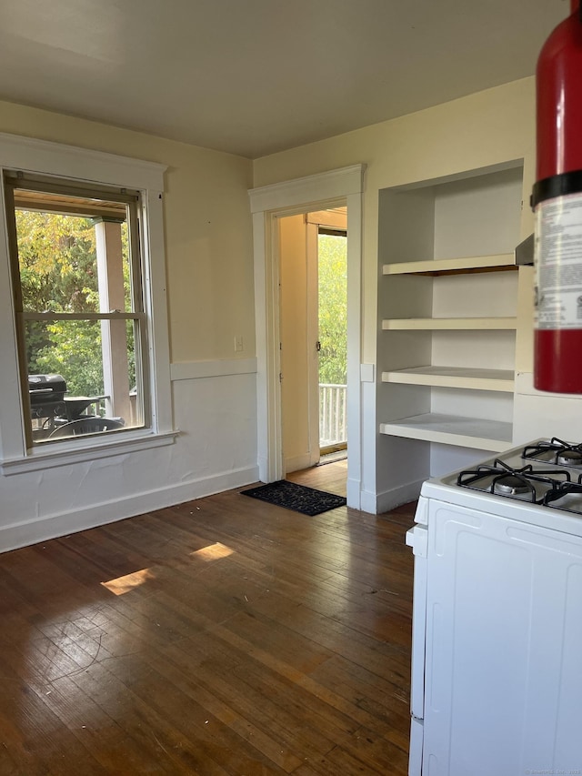 kitchen with white range with gas stovetop, white cabinets, wainscoting, dark wood-style flooring, and open shelves