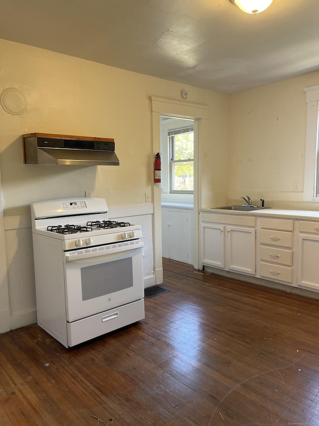 kitchen featuring white gas range oven, dark wood finished floors, light countertops, under cabinet range hood, and white cabinetry