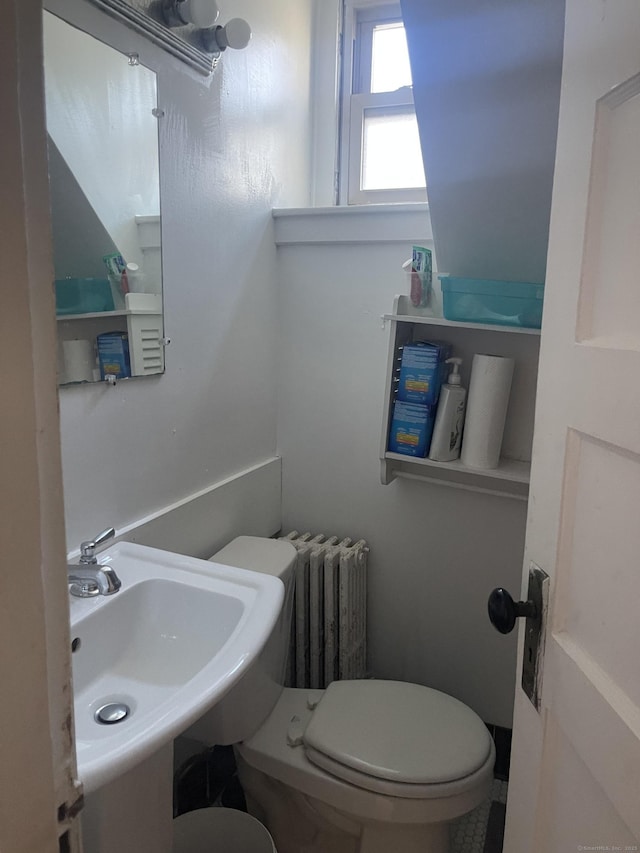 half bathroom with radiator, a sink, and toilet