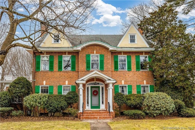 view of front facade with brick siding and a front yard