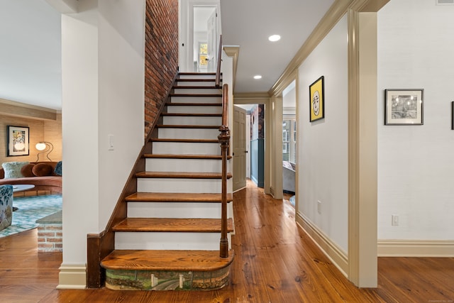 staircase with recessed lighting, baseboards, wood finished floors, and ornamental molding