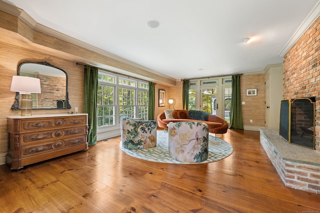 living area with a brick fireplace, a healthy amount of sunlight, and wood finished floors