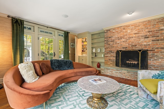 living room featuring built in features, a brick fireplace, and wood finished floors