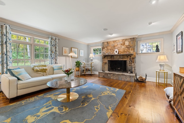 living area featuring ornamental molding, a stone fireplace, baseboards, and wood finished floors