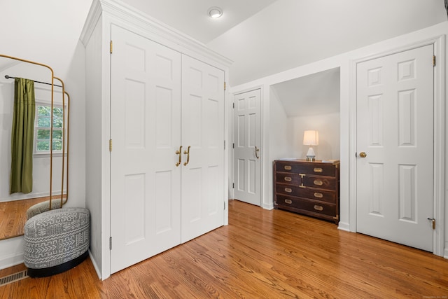 bedroom with baseboards, visible vents, lofted ceiling, light wood-style floors, and a closet