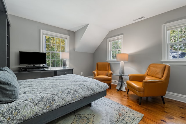 bedroom with baseboards, multiple windows, visible vents, and wood finished floors