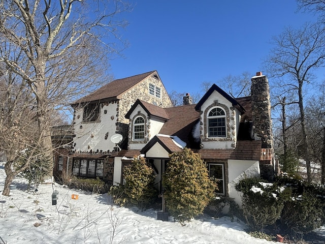 view of front of house with stone siding, a chimney, and stucco siding