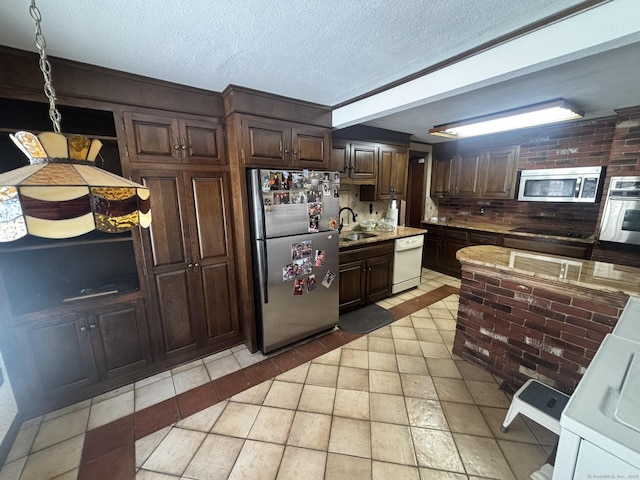 kitchen featuring stainless steel appliances, a sink, a textured ceiling, and dark brown cabinetry