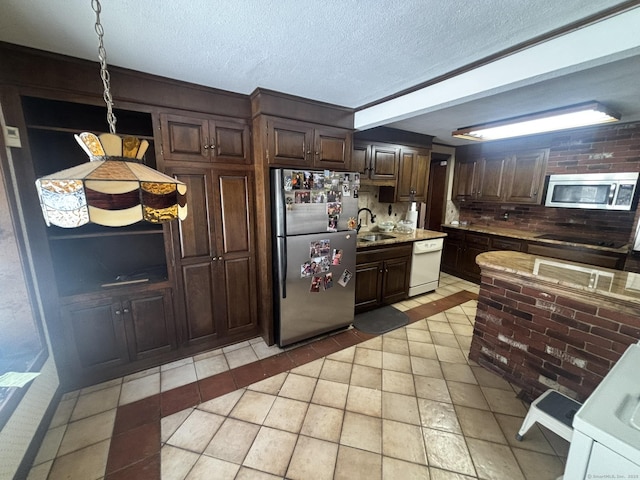 kitchen with stainless steel appliances, dark brown cabinets, a textured ceiling, light countertops, and a sink