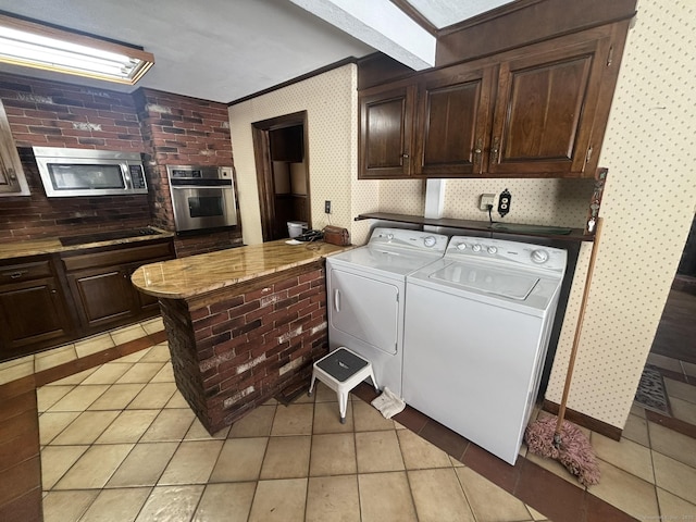 clothes washing area with light tile patterned floors, wallpapered walls, crown molding, and washer and dryer