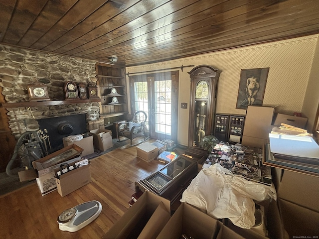 living area featuring wood ceiling, a stone fireplace, and wood finished floors