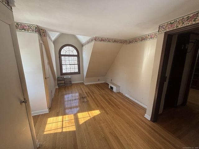 additional living space with lofted ceiling, hardwood / wood-style flooring, and baseboards