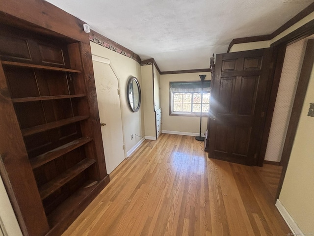 interior space featuring light wood-type flooring, baseboards, and a textured ceiling