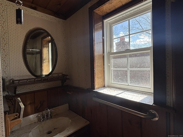 bathroom with wallpapered walls and a sink