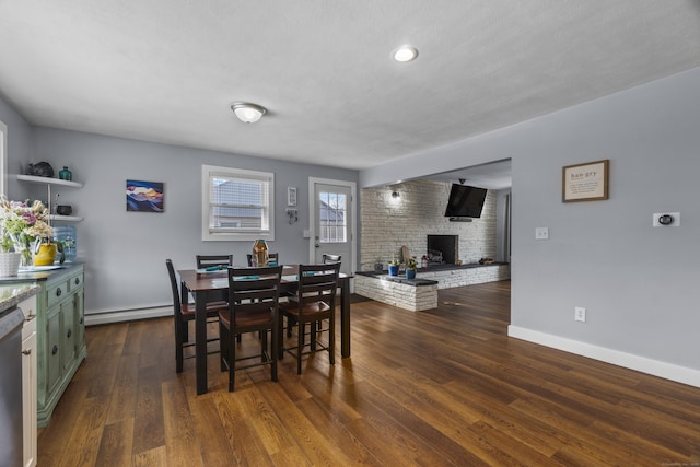 dining space with dark wood-type flooring, baseboards, a fireplace, and baseboard heating