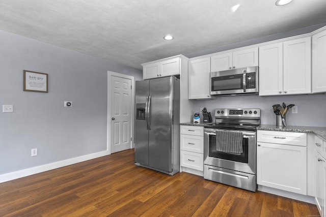 kitchen featuring dark wood-style flooring, baseboards, white cabinets, appliances with stainless steel finishes, and dark stone countertops